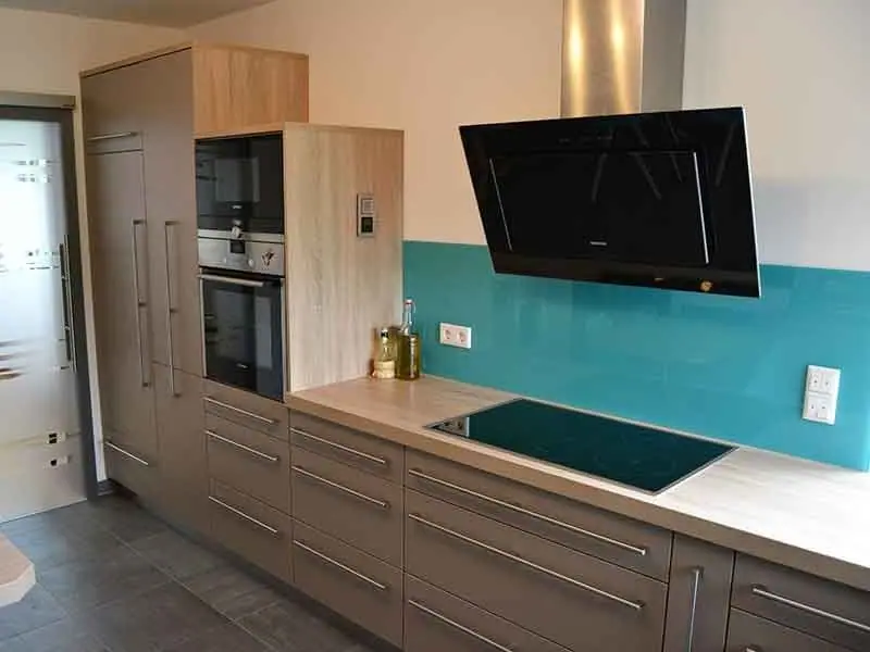 Einbauküche mit Holzfronten, türkiser Rückwand, Backofen und Kochfeld